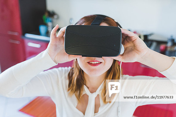 Portrait of young woman in kitchen looking through virtual reality headset
