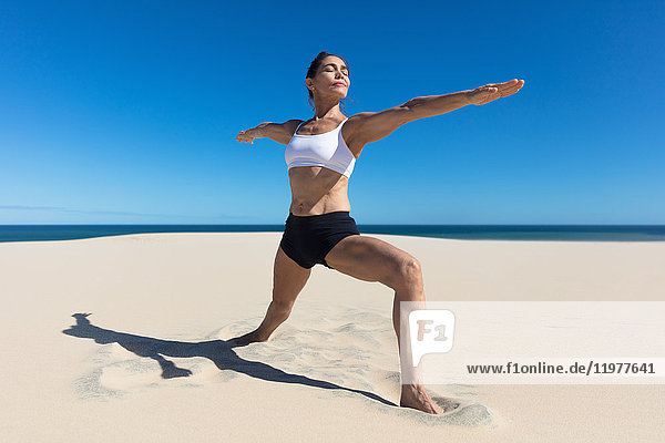 Frau am Strand Arme geöffnet und streckt sich in Yogastellung