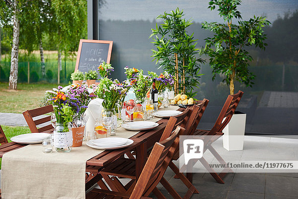 Tisch mit Blumenarrangements und Tellern für das Mittagessen auf der Terrasse
