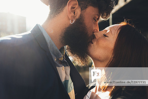 Cool couple kissing on sunlit street