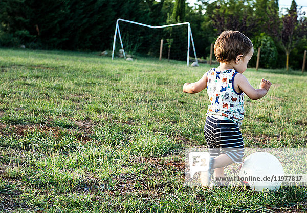 Toddler playing football in park
