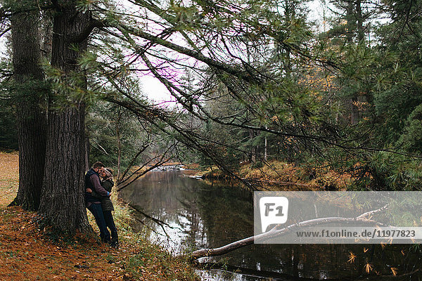 Paar am Fluss  an einen Baum gelehnt  von Angesicht zu Angesicht umarmt  Bancroft  Kanada  Nordamerika
