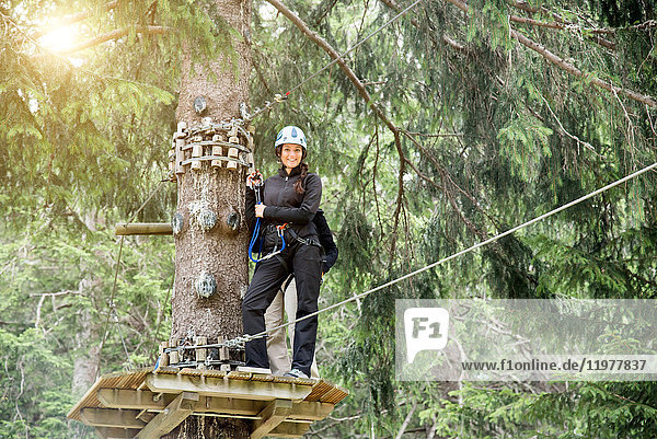 Teenage girl on high rope course looking at camera smiling