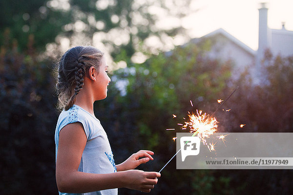 Girl holding sparkler in garden at dusk on independence day  USA