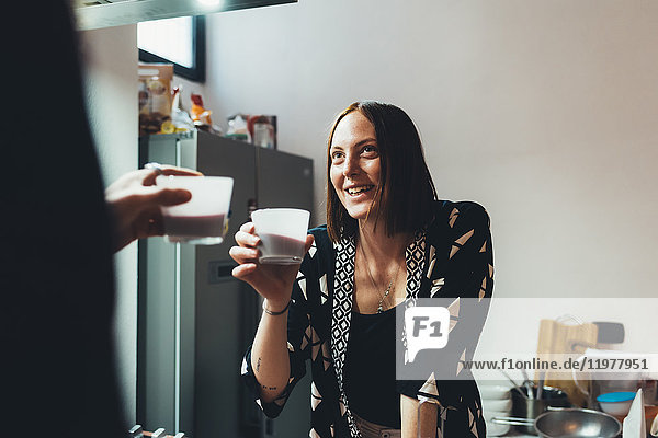 Junge Frau und ihr Freund stoßen in der Küche auf Kaffee an