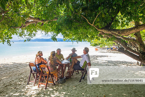 Freunde entspannen sich am Esstisch am Strand  Koh Rang Yai  Thailand  Asien