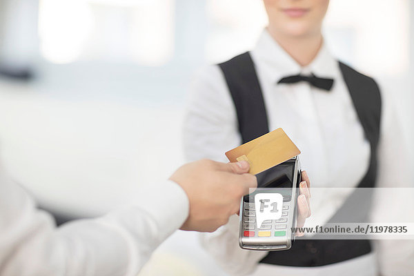 Kellnerin hält Zahlungsautomat in Richtung Kunde,  Kunde bezahlt kontaktlos
