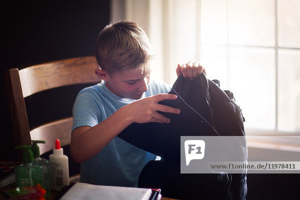 Junge packt Rucksack mit Schulsachen