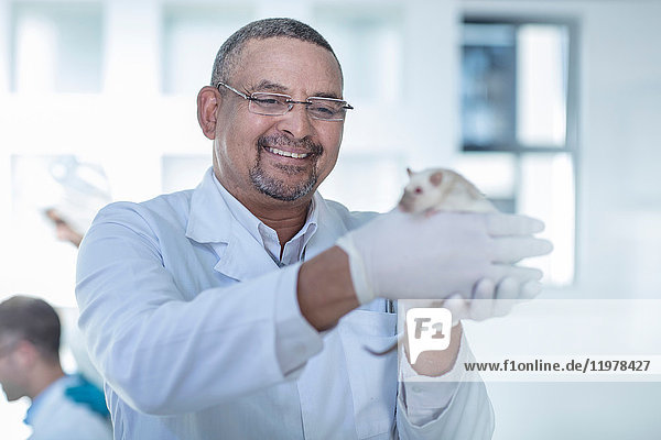 Laborantin hält weiße Ratte  lächelnd