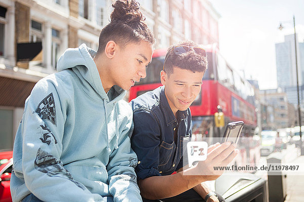 Zwei junge Männer im Freien  die sich ein Smartphone anschauen