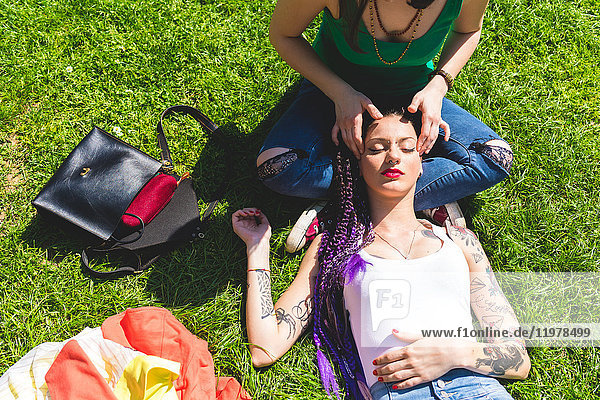 Frau gibt Freundin Kopfmassage auf Gras