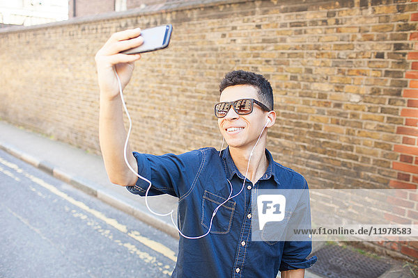 Young man outdoors  taking selfie  using smartphone