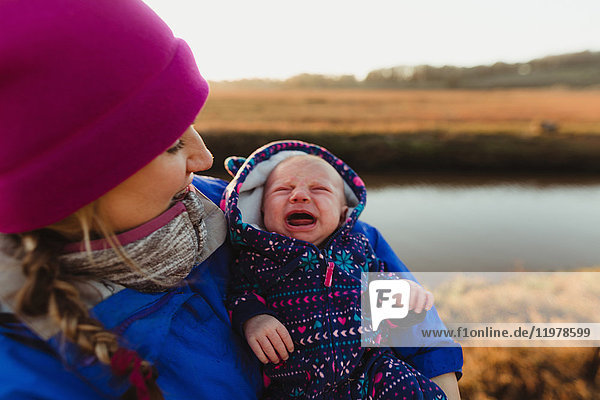Mittlere erwachsene Frau wiegt weinendes Baby am Flussufer  Morro Bay  Kalifornien  USA