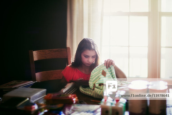 Girl packing backpack with school stationery supplies