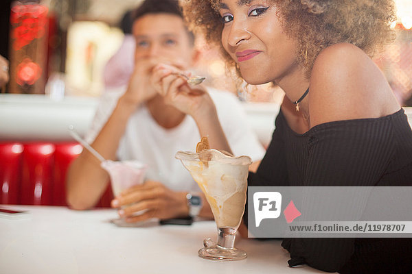 Young couple sitting in diner  eating dessert  smiling