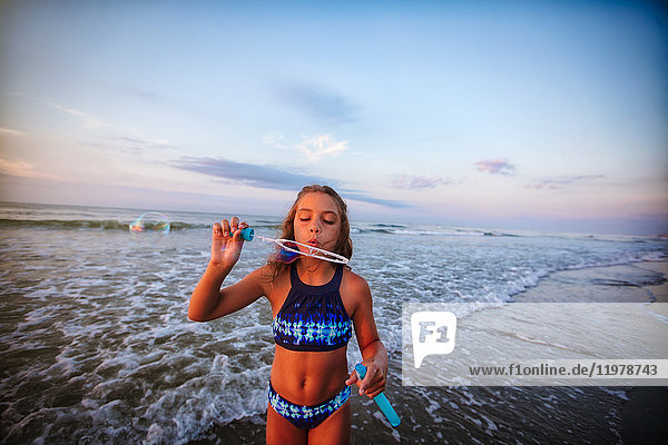 Girl blowing soap bubbles on beach
