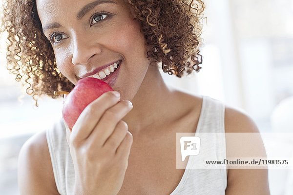 Mittlere erwachsene Frau isst Apfel.