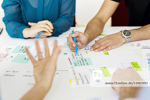 Colleagues sitting by conference table and brainstorming