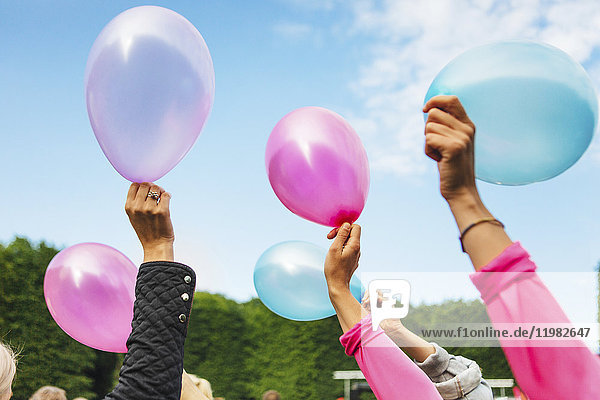 Raised hands holding balloons