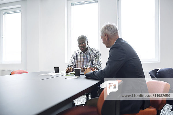 Two architects talking at table in office