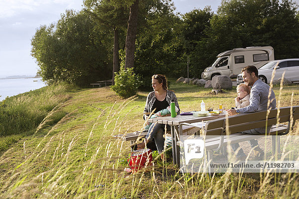 Parents with sons (18-23 0-1 months) sitting by picnic table