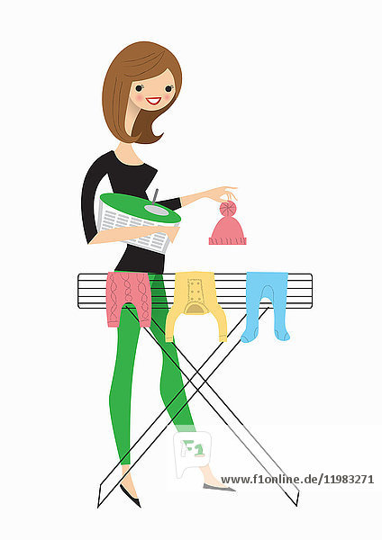 Frau hängt Babykleidung auf den Wäscheständer