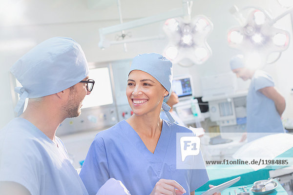Lächelnde Chirurgen im Gespräch im Operationssaal