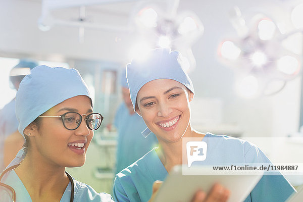 Female surgeons using digital tablet  talking in operating room