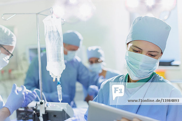 Chirurgin mit chirurgischer Maske und digitalem Tablet im Operationssaal