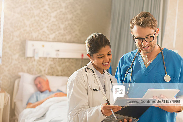 Ärztin und Pfleger bei der Visite  mit digitalem Tablet und Klemmbrett im Krankenhaus