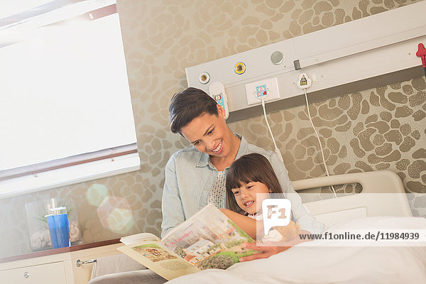 Mutter  die mit ihrer Tochter im Krankenhauszimmer ein Buch liest