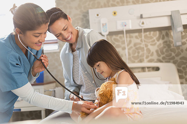 Krankenschwester mit Stethoskop auf Teddybär von Mädchen Patienten im Krankenhaus Zimmer