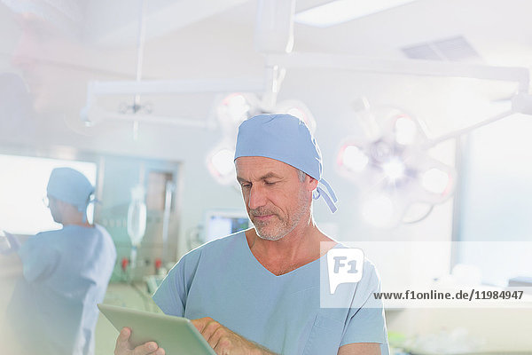 Mature male surgeon using digital tablet in operating room