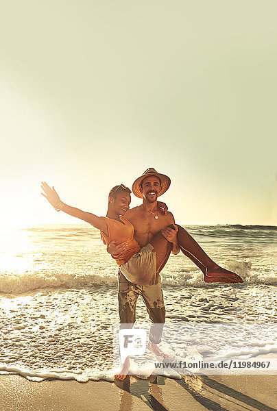 Portrait playful young couple on sunny summer ocean beach