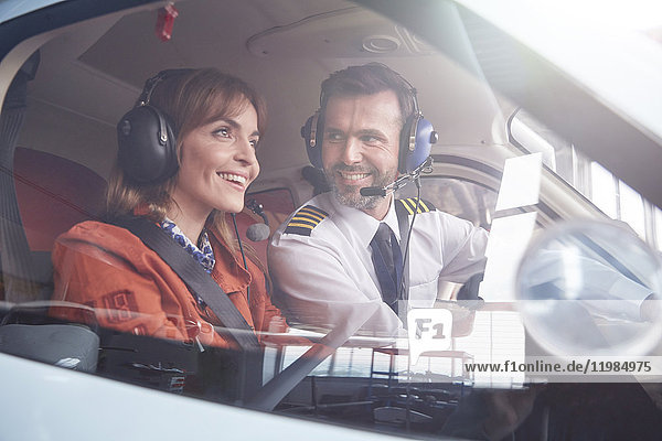 Pilot im Gespräch mit lächelndem Passagier im Flugzeugcockpit