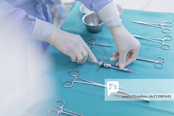 Chirurg mit Gummihandschuhen bereitet chirurgische Instrumente auf einem Tablett vor