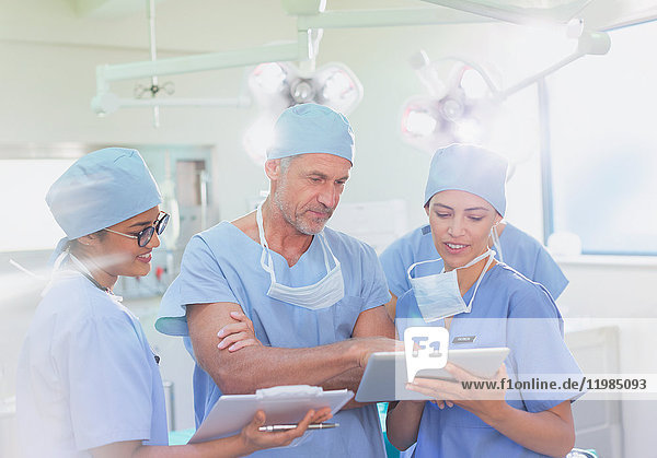 Chirurgen und Krankenschwester verwenden Klemmbrett und digitales Tablet im Operationssaal