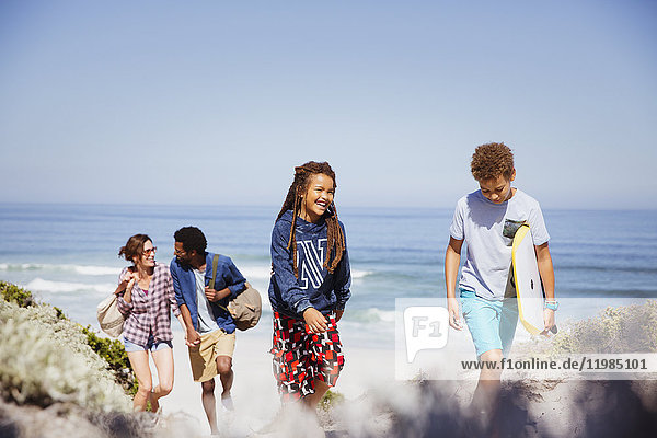 Family walking with boogie board on sunny summer ocean beach