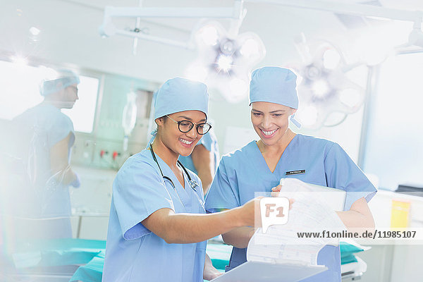Weibliche Chirurgen bei der Durchsicht von Papierkram im Operationssaal