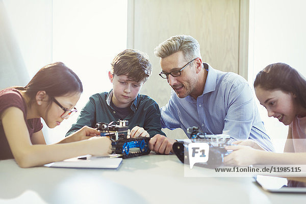 Lehrer hilft Schülern beim Zusammenbau von Robotern im Klassenzimmer