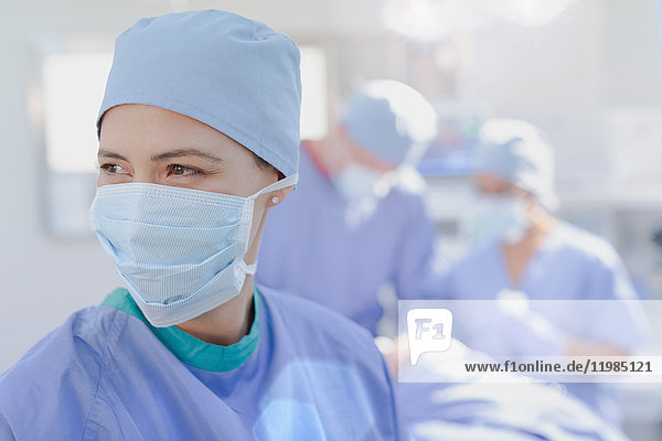 Lächelnde Chirurgin mit chirurgischer Maske im Operationssaal