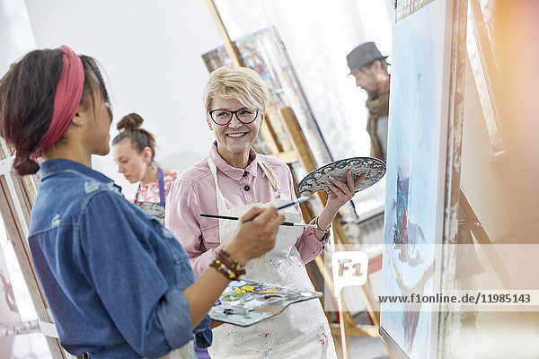 Lächelnde Künstlerinnen mit Pinsel- und Palettenmalerei im Atelier der Kunstklasse