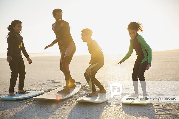 Familien-Surfer üben auf Surfbrettern am sonnigen Sommerstrand