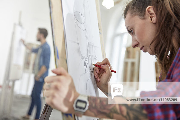 Fokussierte Künstlerin mit Tattoo-Skizze an der Staffelei im Kunststudio