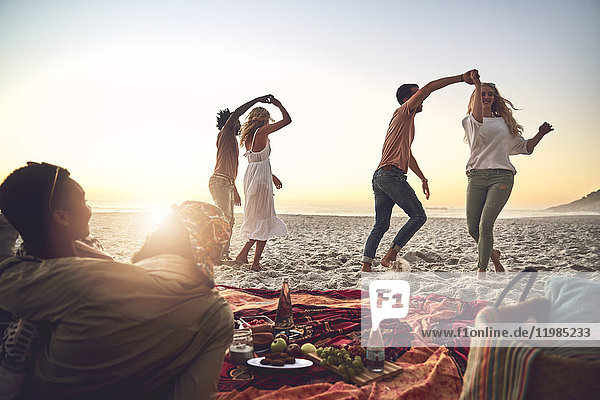 Junge Paare tanzen  genießen Picknick am Sommerstrand