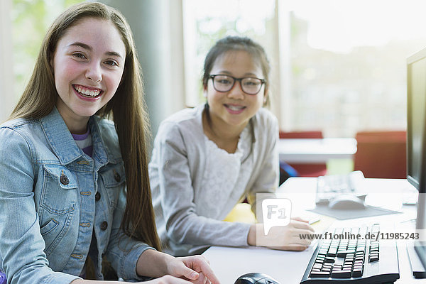 Portrait smiling  confident girl students researching at computer in library