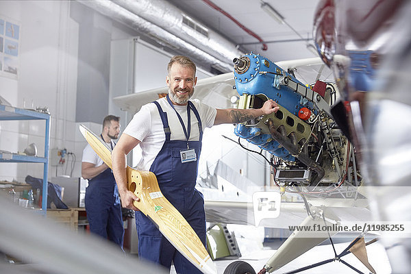 Portrait confident male engineer mechanic working on airplane in hangar