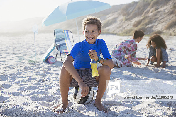 Smiling boy drinking juice on sunny summer beach