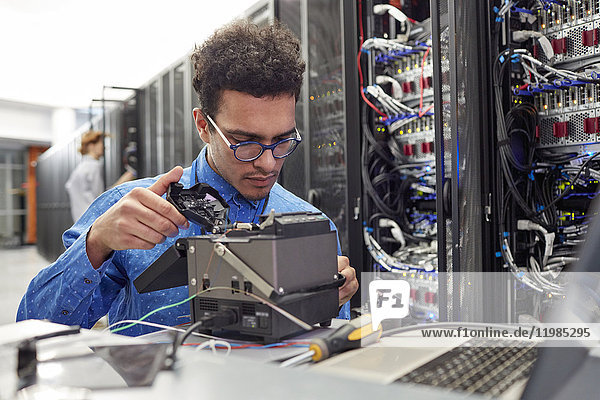 Male IT technician fixing equipment in server room