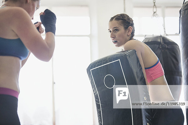 Frauen beim Kickboxen mit Polsterung im Fitnessstudio